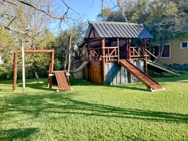 Plaza de juegos de madera con trepadores y tobogán
