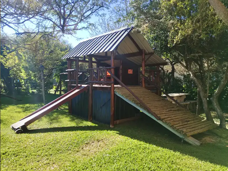 Casita de juegos con rampa, tobogán y sombra natural